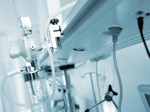 Close-up of medical equipment in a hospital, featuring tubes and gauges under blue lighting, conveying a clinical and sterile environment