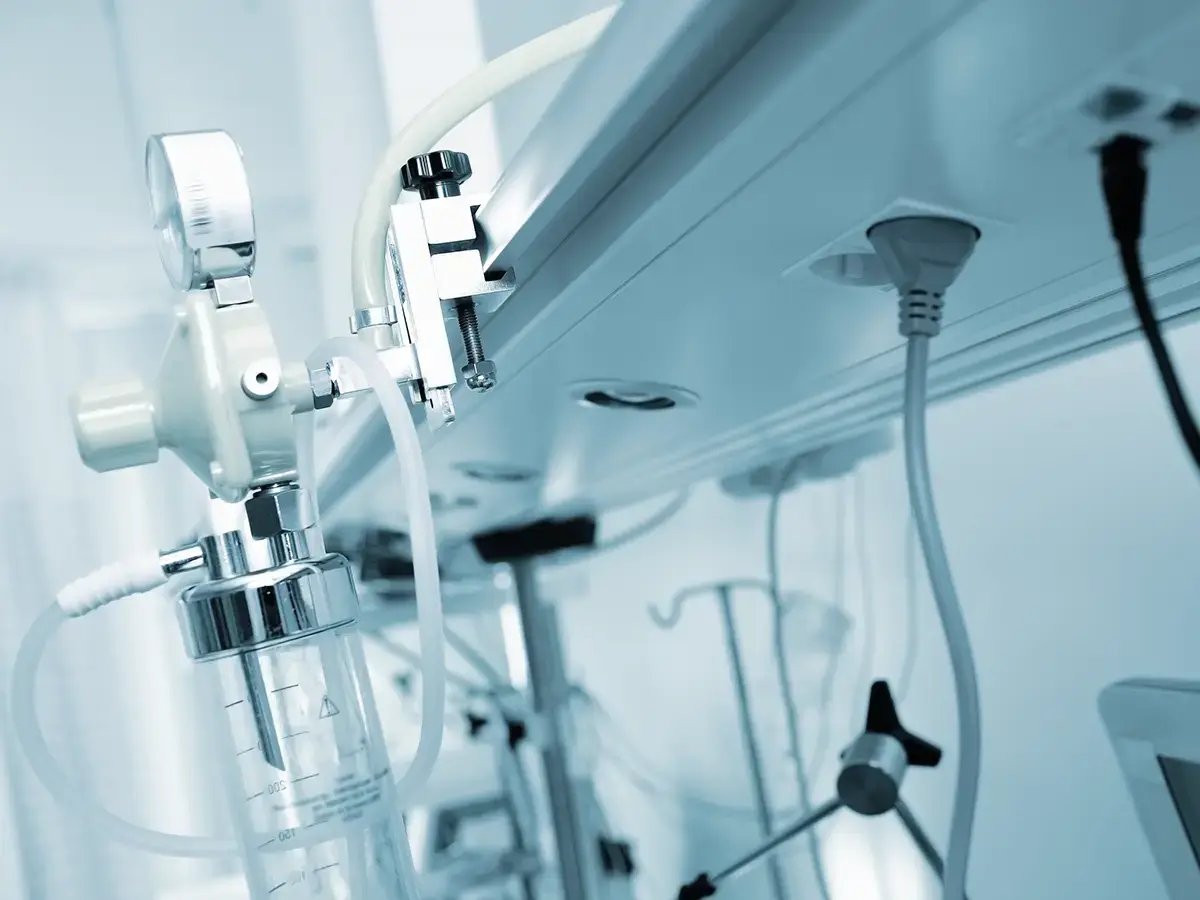 Close-up of medical equipment in a hospital, featuring tubes and gauges under blue lighting, conveying a clinical and sterile environment