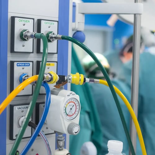 Medical gas panel with labeled connections for oxygen, nitrous oxide, and air, with colored hoses attached